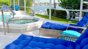 Un área de piscina con jacuzzi, sillas de descanso y vistas al agua.