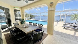 A sunlit room with a pool view, a ceiling fan, and a dining area with chairs and a table. - TOP FLORIDA's Villa Lake View (Cape Coral)