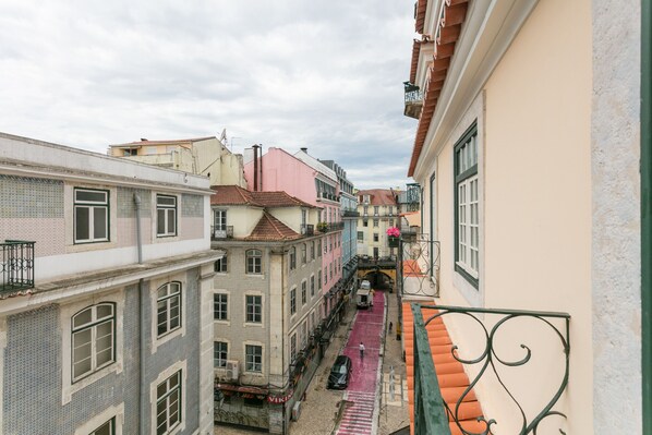 A narrow street with buildings on either side, a pedestrian path, and a small bridge.