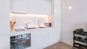 A modern kitchen with white cabinetry, a built-in oven, a sink, and a toaster. - FLH Chiado Modern Place (Lisbon)