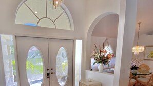 A spacious entryway with a double door, a small side table, and a chair. - TOP FLORIDA's Villa Parrot Key (Cape Coral)
