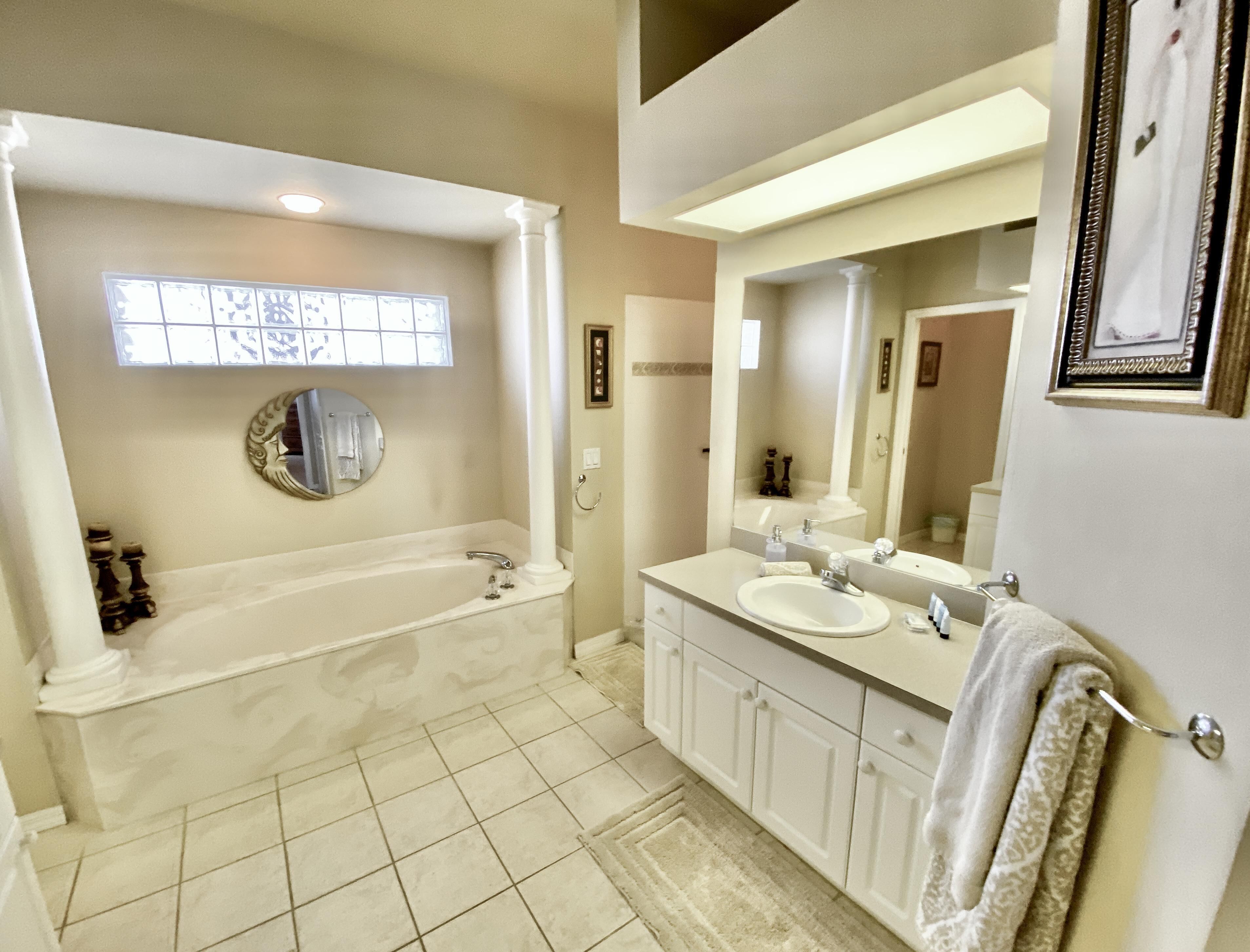 A bathroom with a bathtub, a sink, and a large mirror.
