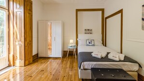 Ein Schlafzimmer mit Holzboden, einem Bett mit Kissen, einem Nachttisch mit Lampe und einem Kleiderschrank.