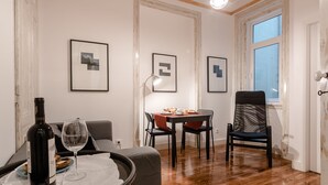 Un comedor con una mesa, sillas, una botella de vino y una copa sobre una bandeja.