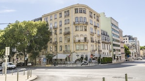 Un edificio de varios pisos con fachada curva, balcones y un café en la planta baja.