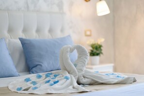 A neatly made bed with a white and blue blanket, a blue pillow, and a white headboard. - Alma Adry (Naples)