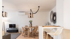 Un salon moderne avec une table de salle à manger ronde, un canapé et un téléviseur posé sur un meuble noir.