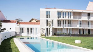 Un bâtiment moderne doté d’une piscine, d’une pelouse bien entretenue et surplombant un ciel bleu azur.