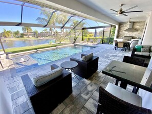 A poolside area with outdoor seating, a view of a lake, and a kitchen area. - TOP FLORIDA's Villa Sunrise (Cape Coral)