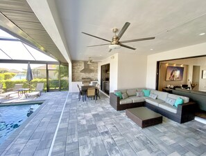 A modern outdoor living area with a pool, a ceiling fan, and a seating arrangement.