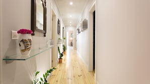 A hallway with a glass shelf holding a decorative vase, potted plants, and wall-mounted mirrors. - FLH Marquês Trendy Apartment (Lisboa ciudad)