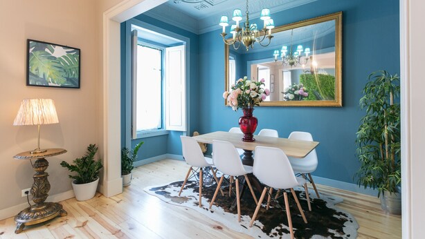 A dining area with a table, chairs, a chandelier, a mirror, and potted plants. - FLH Marquês Trendy Apartment (Lisboa ciudad)