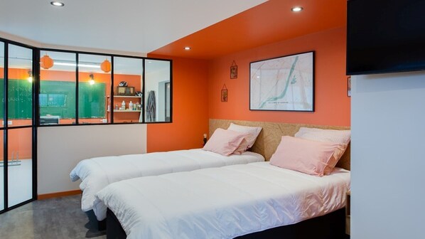 Une chambre d’hôtel avec deux lits, un mur d’accent de couleur orange, une grande fenêtre et une carte accrochée au mur.