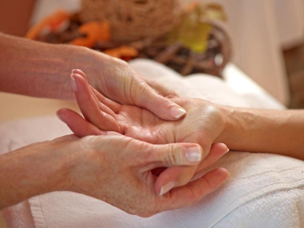 A close-up of hands, one appearing to be an elderly person and the other a younger individual, possibly in a caregiving or comforting scenario.