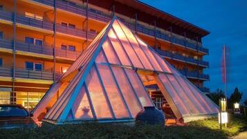 A modern building with a unique triangular glass structure in front.