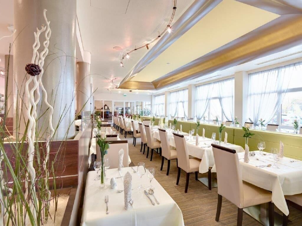 A restaurant with multiple tables, each set with white tablecloths, plates, and cutlery.