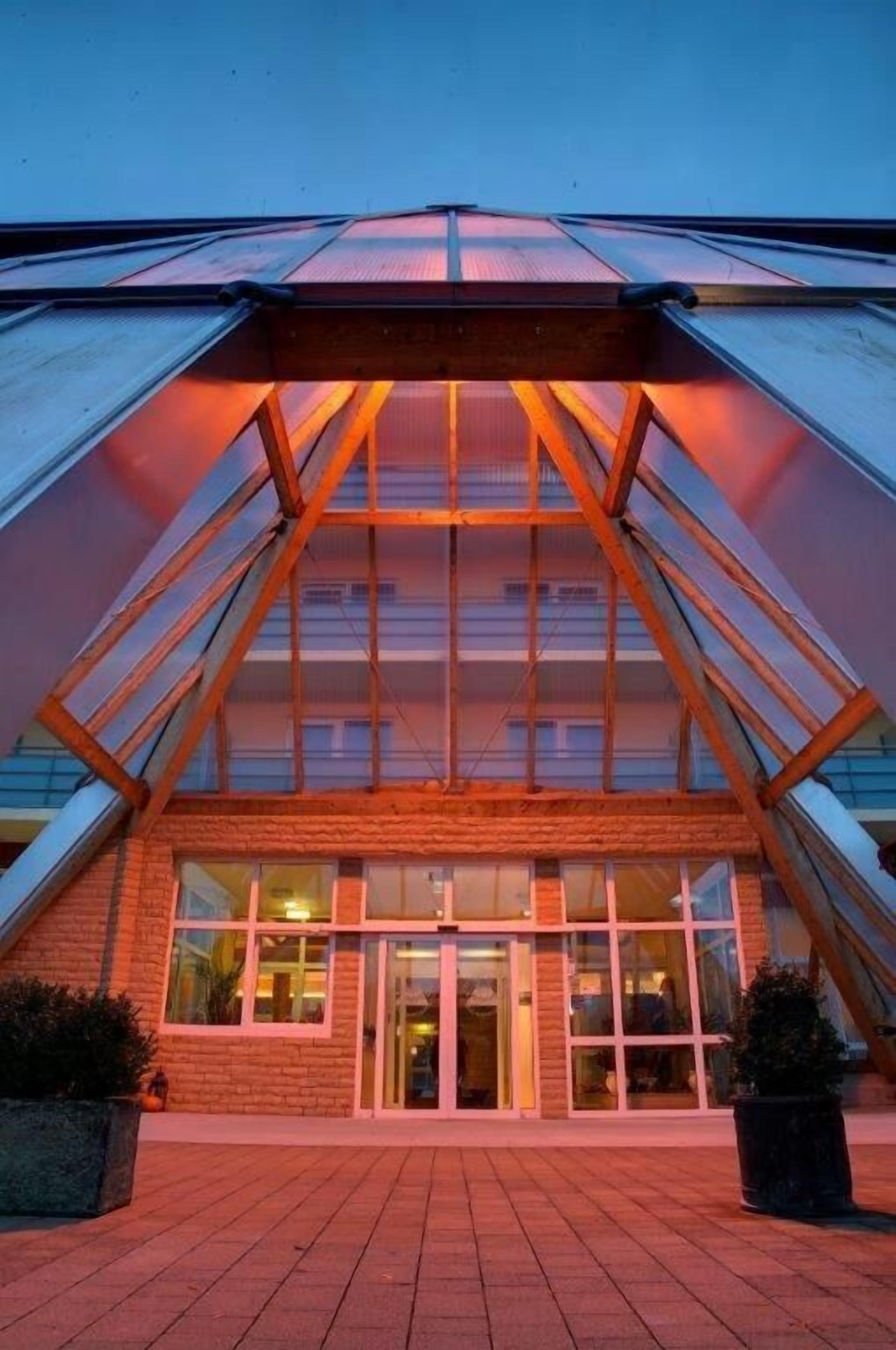 A building with a glass facade, a brick base, and a triangular roof structure.