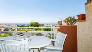 A balcony with a white table and chairs, overlooking a coastal view. - 126-APARTMENT WITH VIEWS OF THE PORT OF ROSES (Roses)