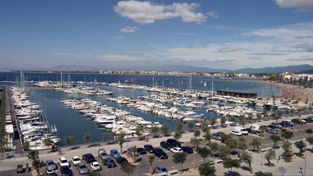 A marina with numerous boats docked, a parking area with cars, and a beach in the background. - 126-APARTMENT WITH VIEWS OF THE PORT OF ROSES (Roses)