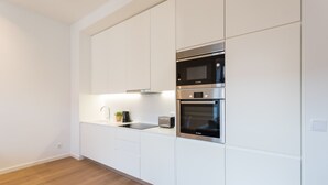 A modern kitchen with white cabinetry, a built-in microwave, oven, and a sink.