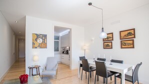 Un soggiorno moderno con zona pranzo, cucina sullo sfondo e opere d'arte alle pareti.