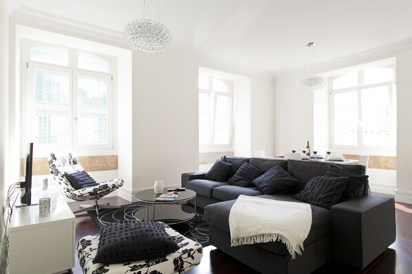 A modern living room with a black sofa, a patterned armchair, and a coffee table.