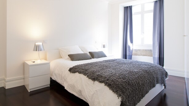 Un dormitorio con cama, mesita de noche y lámpara.