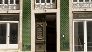 Fachada de edificio con diseño de ladrillo verde, un acceso decorativo y dos puertas con la etiqueta 'mandala 66'.