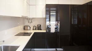 Uma cozinha moderna com armários brancos, uma geladeira preta e eletrodomésticos de aço inoxidável.