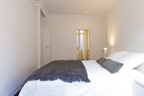 A hotel room with a bed, a nightstand, a lamp, and a door leading to a bathroom.