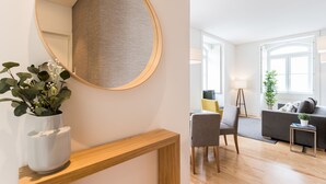 A modern living room with a round mirror, a wooden console table, a grey sofa, and a small side table. - FLH Downtown Fantastic Flat (Lisbon)