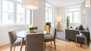 A modern living room with a round dining table, grey sofas, and a small side table. - FLH Downtown Fantastic Flat (Lisbon)
