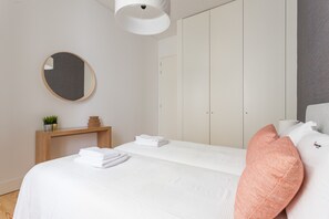 Um quarto moderno com cama, mesa de cabeceira, espelho e guarda-roupa.