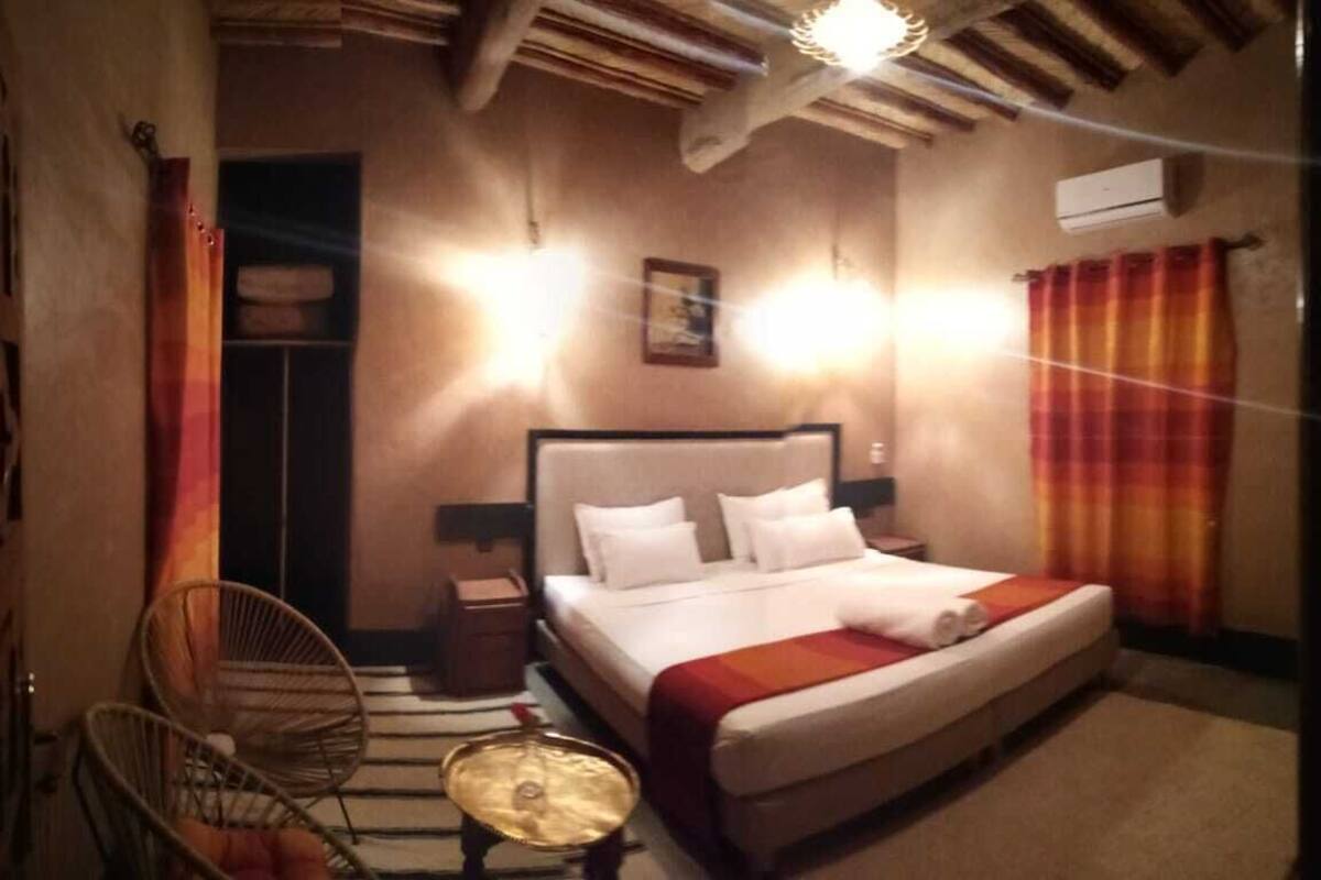 A bedroom with a bed, bedside tables, a chair, and a small table.