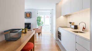A modern kitchen with a sink, toaster, and a dining area with a chair and table.