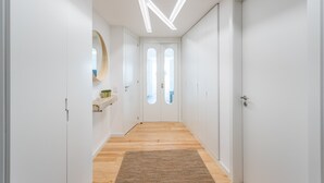 A modern hallway with white walls, wooden flooring, and a central door with a window. - FLH Chiado Bright Apartment (Lisboa ciudad)