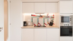 A modern kitchen with white cabinets, a stainless steel microwave, and a coffee maker. - FLH Chiado Bright Apartment (Lisboa ciudad)