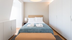 A modern hotel room with a large bed, a bedside table with a lamp, and a wardrobe. - FLH Chiado Bright Apartment (Lisboa ciudad)