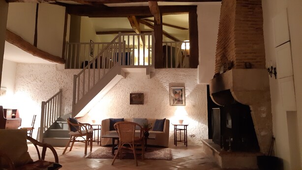 A cozy living room with a fireplace, a staircase, and a dining area.