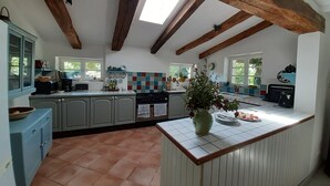 A kitchen with a tiled floor, wooden beams, a window, and a sink.
