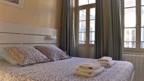 Quarto de hotel com cama, almofadas e janela com cortinas.