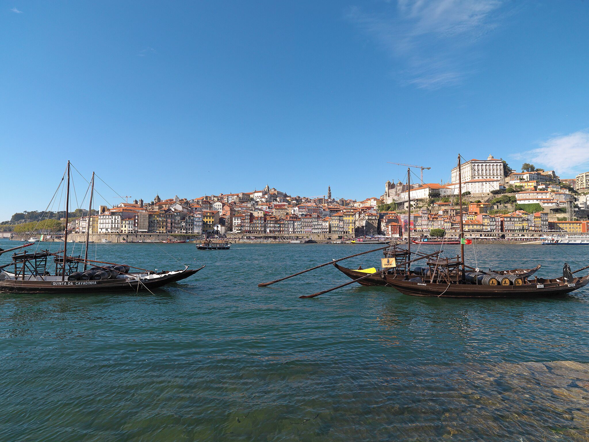 A harbor with boats and a historic cityscape in the background.
