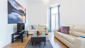 Een moderne woonkamer met een groot schilderij, een bank, een salontafel en een televisie.
