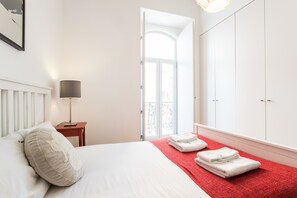 A hotel room with a bed, a nightstand, a lamp, a red towel on the floor, and a wardrobe.