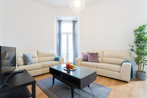 A living room with two sofas, a coffee table, a TV, and a potted plant.