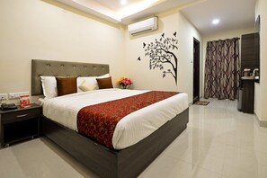 A hotel room with a large bed, a nightstand, a wall-mounted air conditioner, a door with a curtain, and a tiled floor. - Hotel Lotus Grand (Hyderabad)