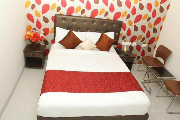 A neatly made bed with a red and white bedspread, a tufted headboard, and multiple pillows. - Hotel Lotus Grand (Hyderabad)