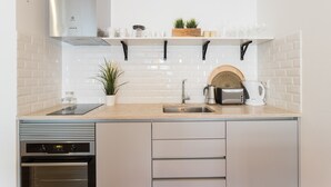 Una cocina moderna con campana extractora de acero inoxidable, horno empotrado, lavamanos y encimera con cafetera y tostadora.