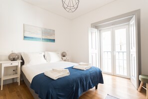A bedroom with a large bed, a nightstand, a lamp, and a painting on the wall.
