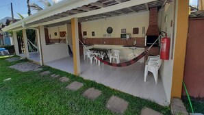 A covered outdoor area with a dining table and chairs, a hammock, and a fire extinguisher. - Recanto Soga Chalés (Ubatuba)